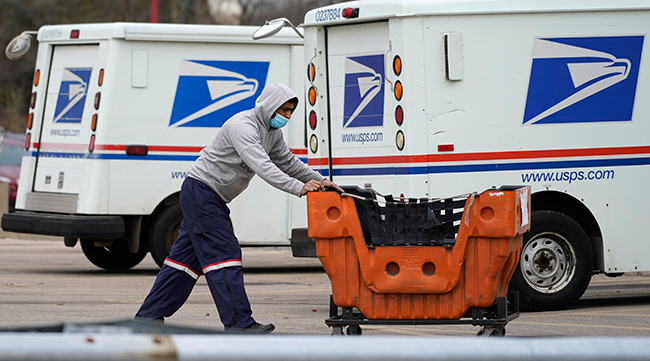 A United States Postal Service employee works outside a post office