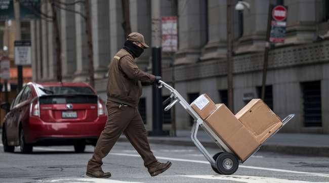 A UPS delivery driver pushes a hand truck loaded with packages in San Francisco.
