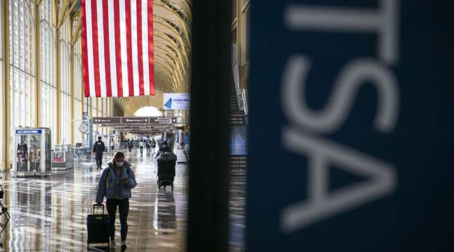 Travelers wearing protective masks walk through Ronald Reagan National Airport. (Sarah Silbiger/Bloomberg News)