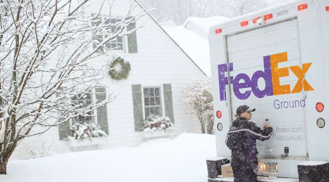 FedEx Ground truck and driver in snow next to house