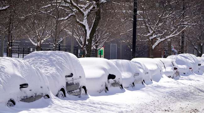 Cars parked for several days in Chicago Feb. 16, 2021 are covered in cumulative snow.