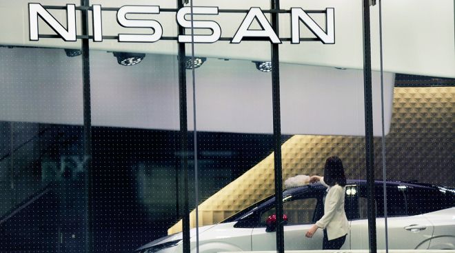 A Nissan showroom employee cleans a car